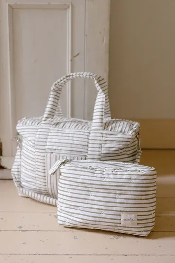Close-up of Pehr organic cotton canvas texture — natural light, warm tones, pom pom detail visible.
